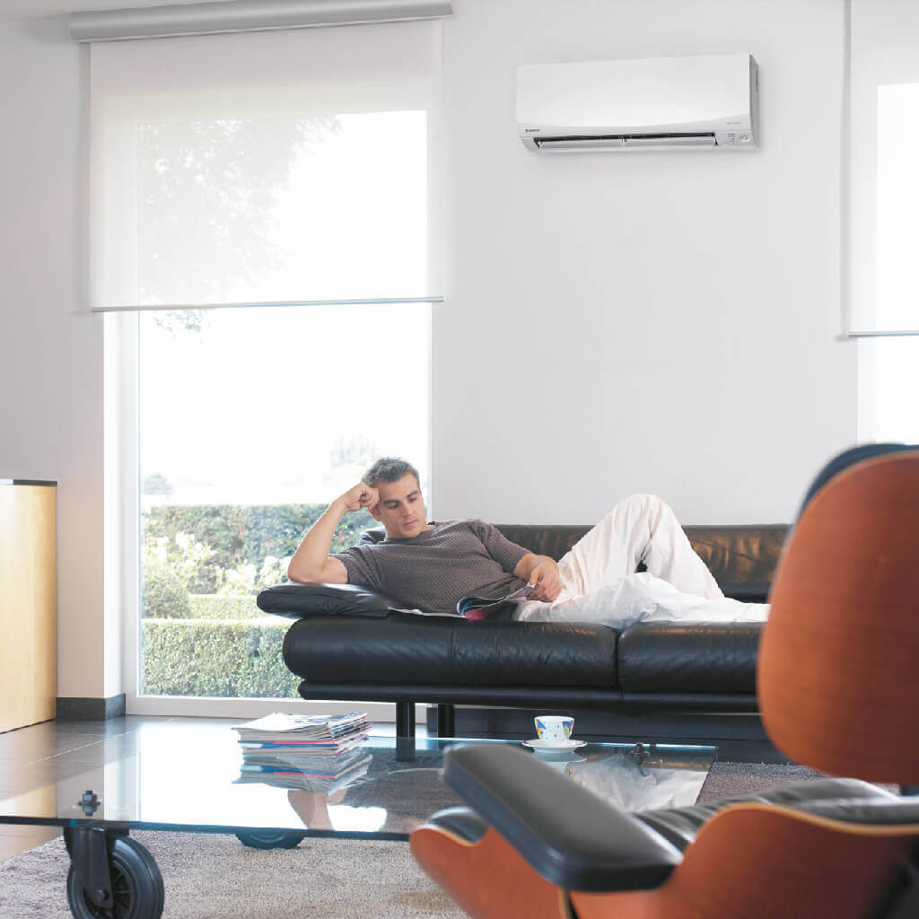 Man laying on couch enjoying Daikin Installation of reverse cycle split system Air Conditioning unit in Gold Coast.